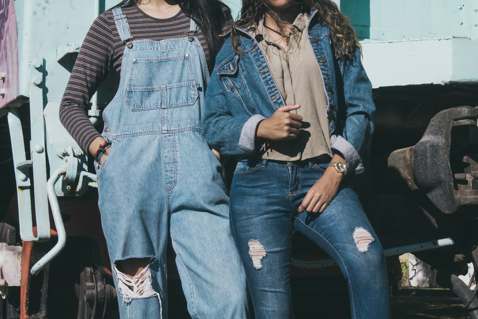 Two women wearing denim — a trucker jacket with jeans, and denim dungarees