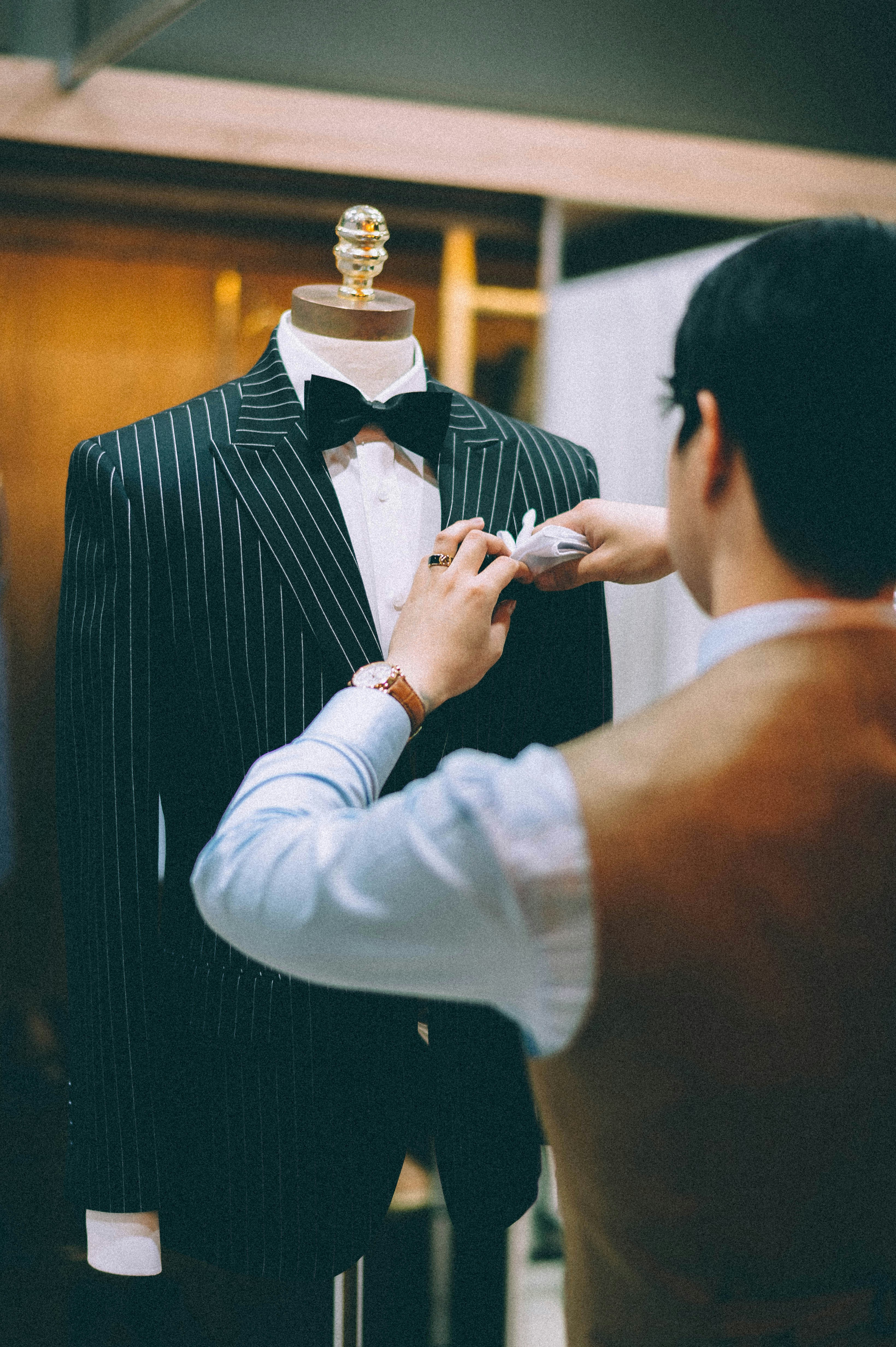 Rail of tailored blazers in navy, tan, grey and cream beside rolls of suiting fabric