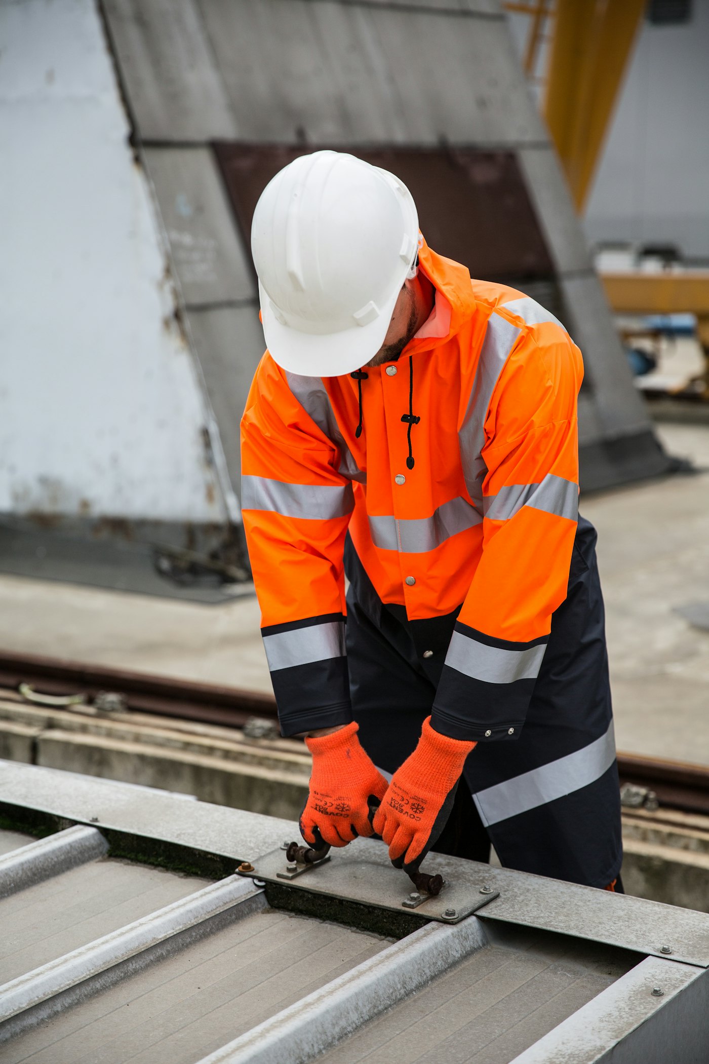 Worker in an orange hi-visibility work jacket with reflective tape